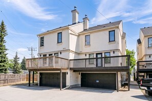 Un immeuble résidentiel de deux étages doté d’un balcon, d’un garage et surplombant un ciel dégagé.