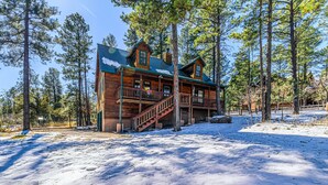 A log cabin with a wooden exterior, a balcony, and a staircase leading to the entrance. - Mescalero Cabin Pet Friendly | Your Adventure Basecamp w/ Grill, Decks & Cozy Comfort (Alto)