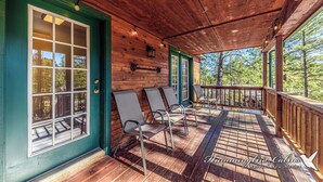 A covered porch with wooden flooring, metal chairs, and a wooden railing. - Mescalero Cabin Pet Friendly | Your Adventure Basecamp w/ Grill, Decks & Cozy Comfort (Alto)
