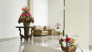 A modern lobby with a seating area, a large floral arrangement, and a small table with a vase. - Hotel Sepanak by Amazing (Central Curup)