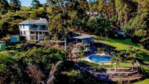 A large house with a swimming pool surrounded by lush greenery and trees.