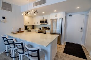 A modern kitchen with white cabinets, stainless steel appliances, and a central island with bar stools.