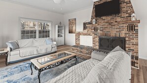 A living room with a fireplace, a sofa, a coffee table, and a ceiling fan.
