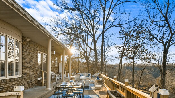 A covered outdoor patio with seating and a view of the surrounding landscape.