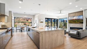 A modern kitchen with a central island, large windows, and a fireplace. - Panoramic Views, High End & Modern Decor, Walk To Tlaquepaque, Hot Tub (Sedona)