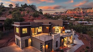 A modern two-story house with a stone facade, large windows, and a patio area. - Panoramic Views, High End & Modern Decor, Walk To Tlaquepaque, Hot Tub (Sedona)