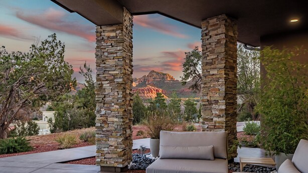 A covered patio with stone pillars, outdoor seating, and a view of a mountain range. - Panoramic Views, High End & Modern Decor, Walk To Tlaquepaque, Hot Tub (Sedona)