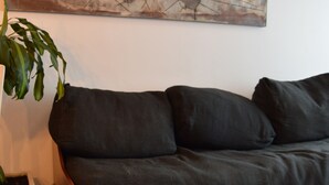 A living room with a dark-colored sofa, a large abstract painting on the wall, and a potted plant. - Siena I    (Villa Carlos Paz)