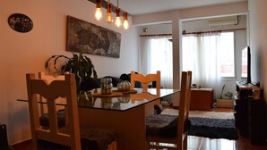 A dining area with a glass table, wooden chairs, and a hanging light fixture. - Siena I    (Villa Carlos Paz)