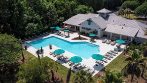 A pool area with lounge chairs and umbrellas, surrounded by lush greenery. - Savannahe Friendly Guest House (Pooler)