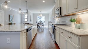 A kitchen with white cabinetry, granite countertops, and pendant lighting. - Savannahe Friendly Guest House (Pooler)