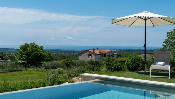 A swimming pool with a clear view of a house and landscape in the background.