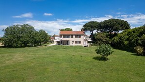 A two-story house with a red-tiled roof, surrounded by a well-maintained lawn and large trees.