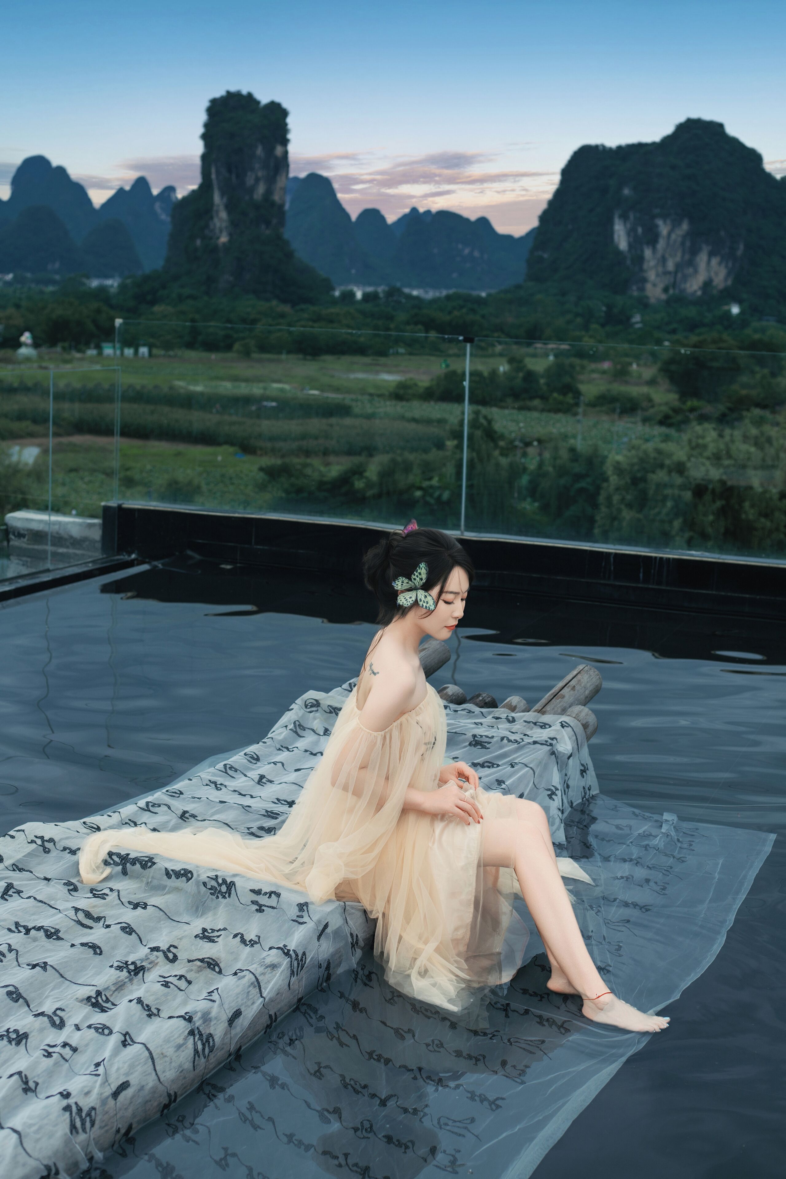 A person sitting on a rooftop terrace with a view of mountains.