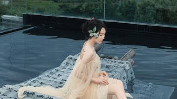 A person sitting on a rooftop terrace with a view of mountains.