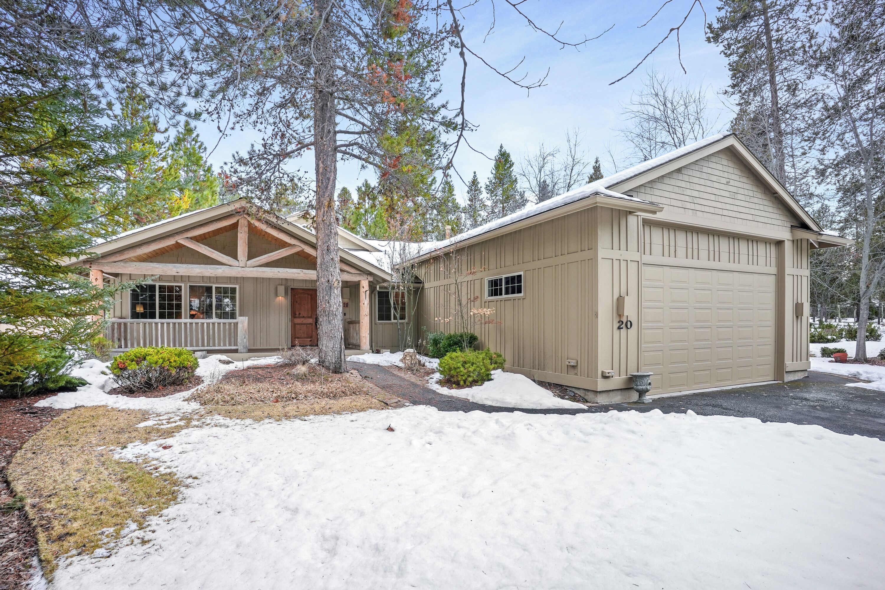 A two-story house with a garage, surrounded by trees and a snow-covered driveway.