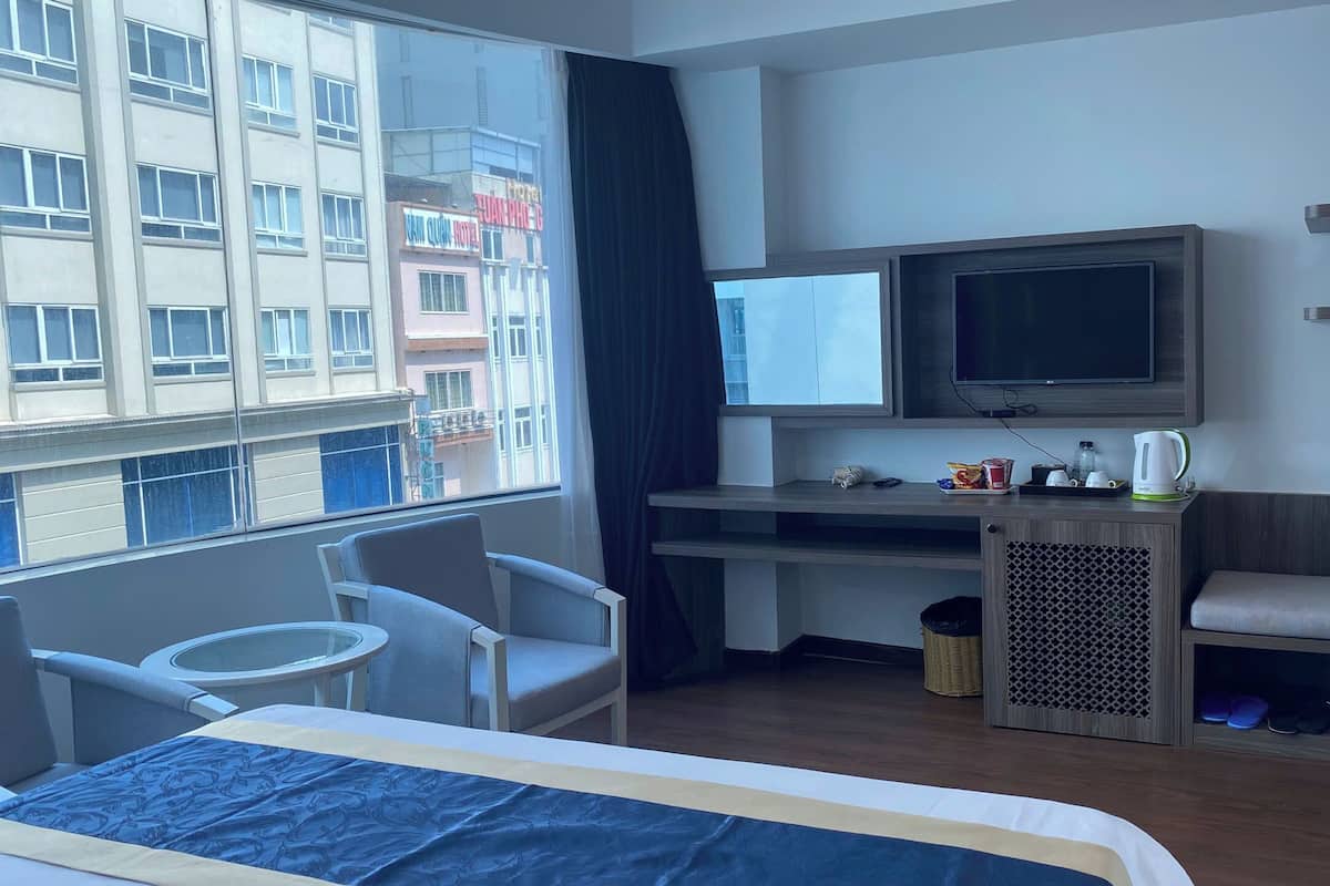 Een hotelkamer met een bed, een bureau met een televisie, een kleine tafel en een stoel.