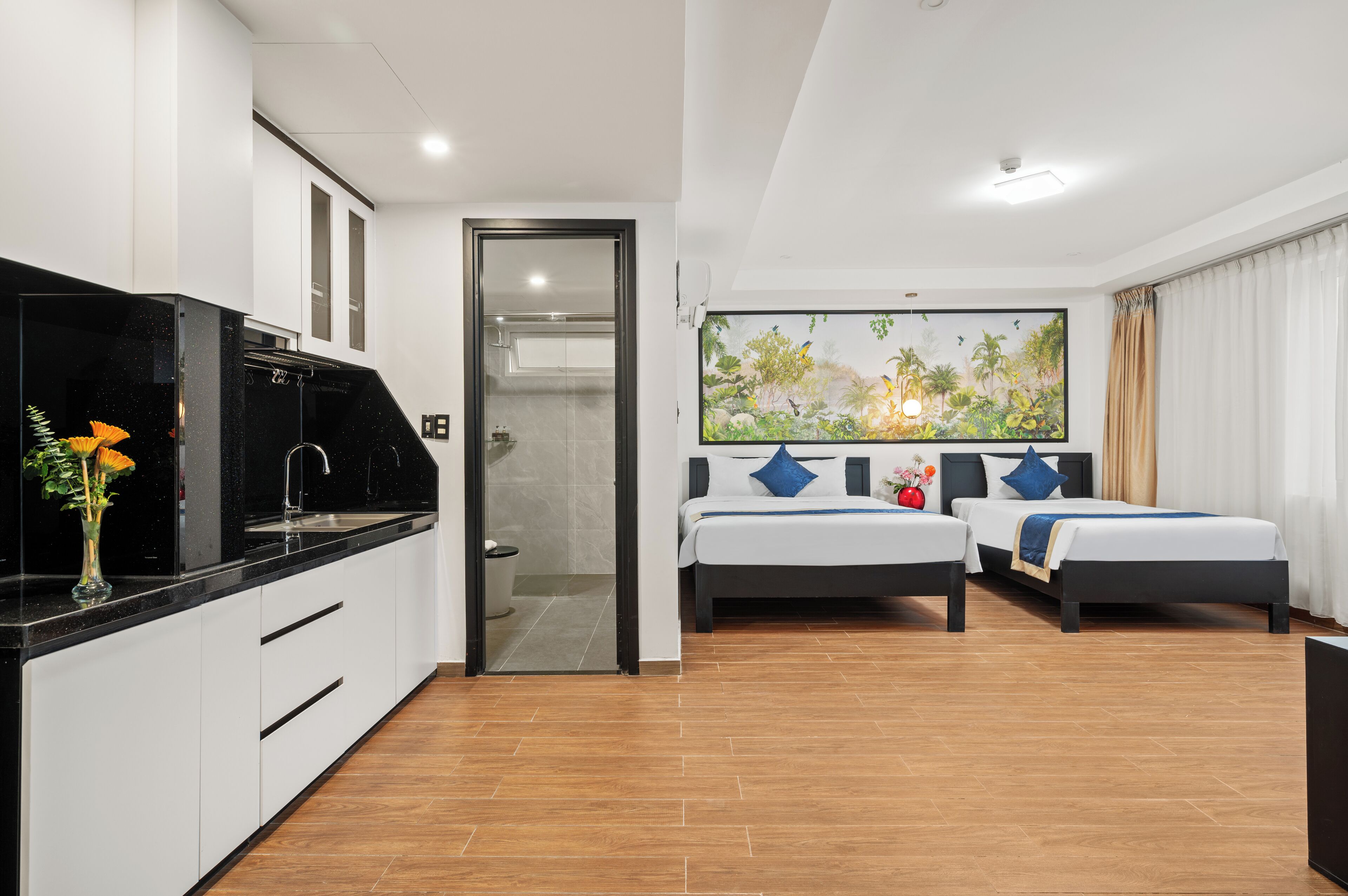Habitación de hotel con kitchenette, dos camas, un ventanal con vistas y un cuadro en la pared.