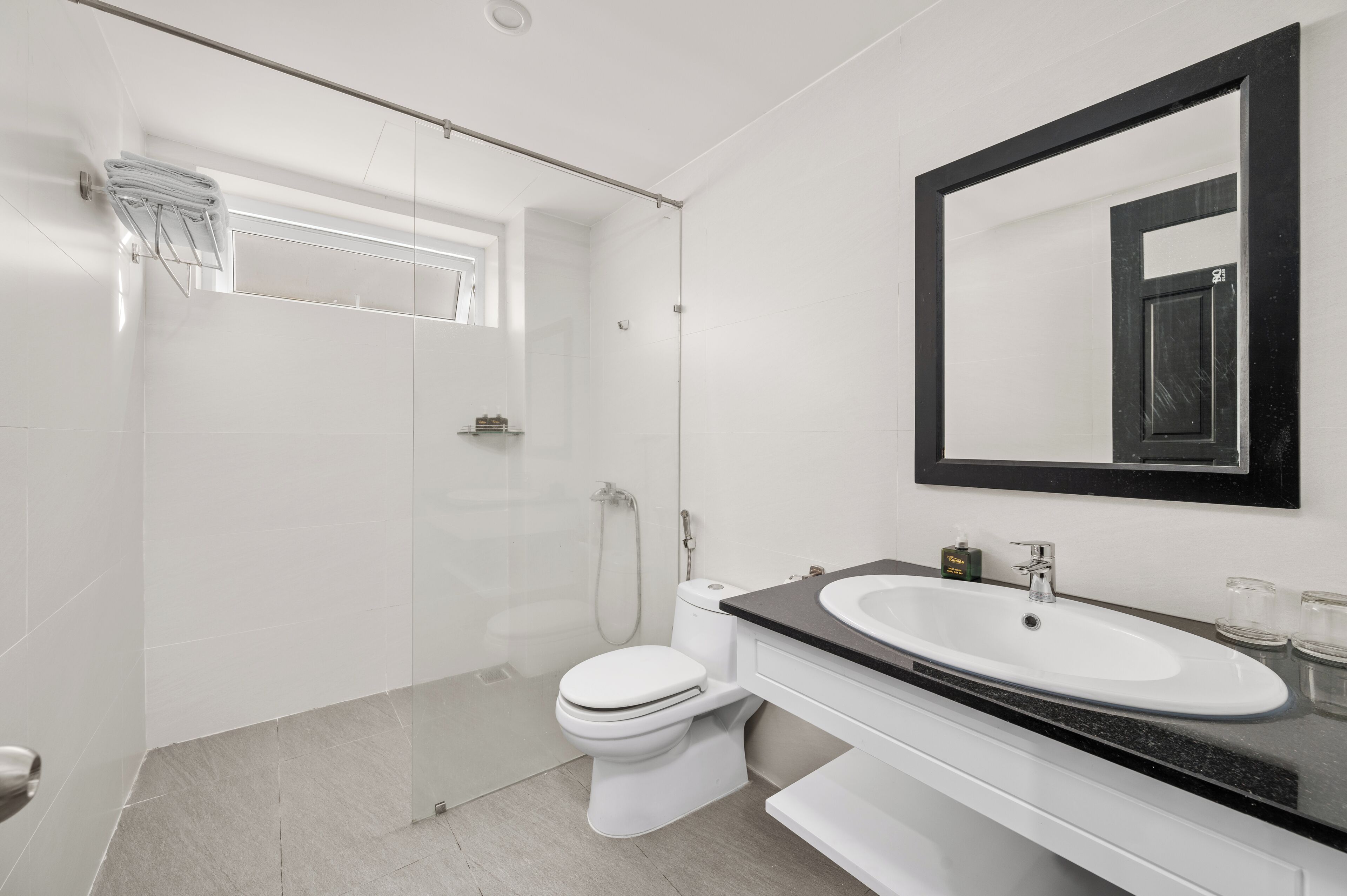 A modern bathroom with a glass-enclosed shower, a white toilet, and a black countertop sink.