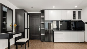 A modern kitchen with white and black cabinetry, a black refrigerator, and a wooden floor.