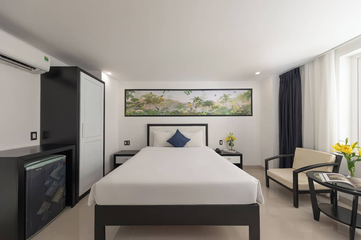 Een hotelkamer met een bed, een bureau, een stoel, een televisie en een schilderij aan de muur.