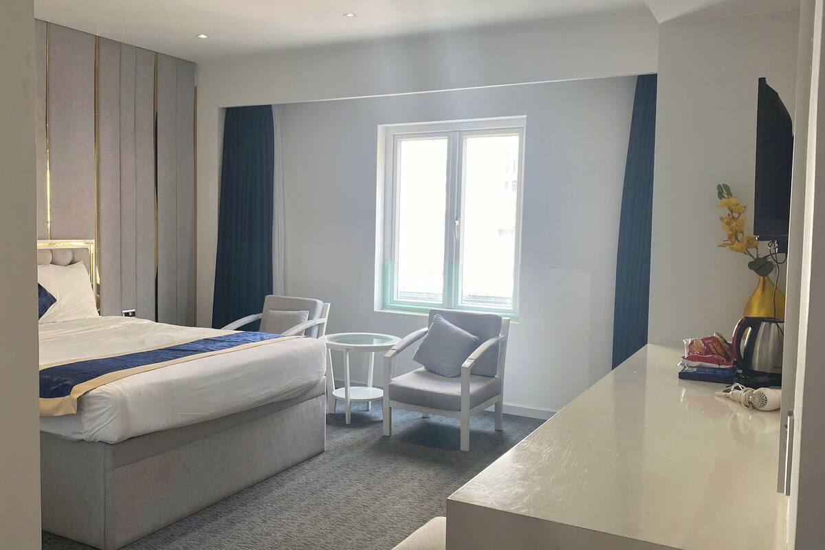Een hotelkamer met een bed, een kleine tafel, een stoel, een bureau en een raam.