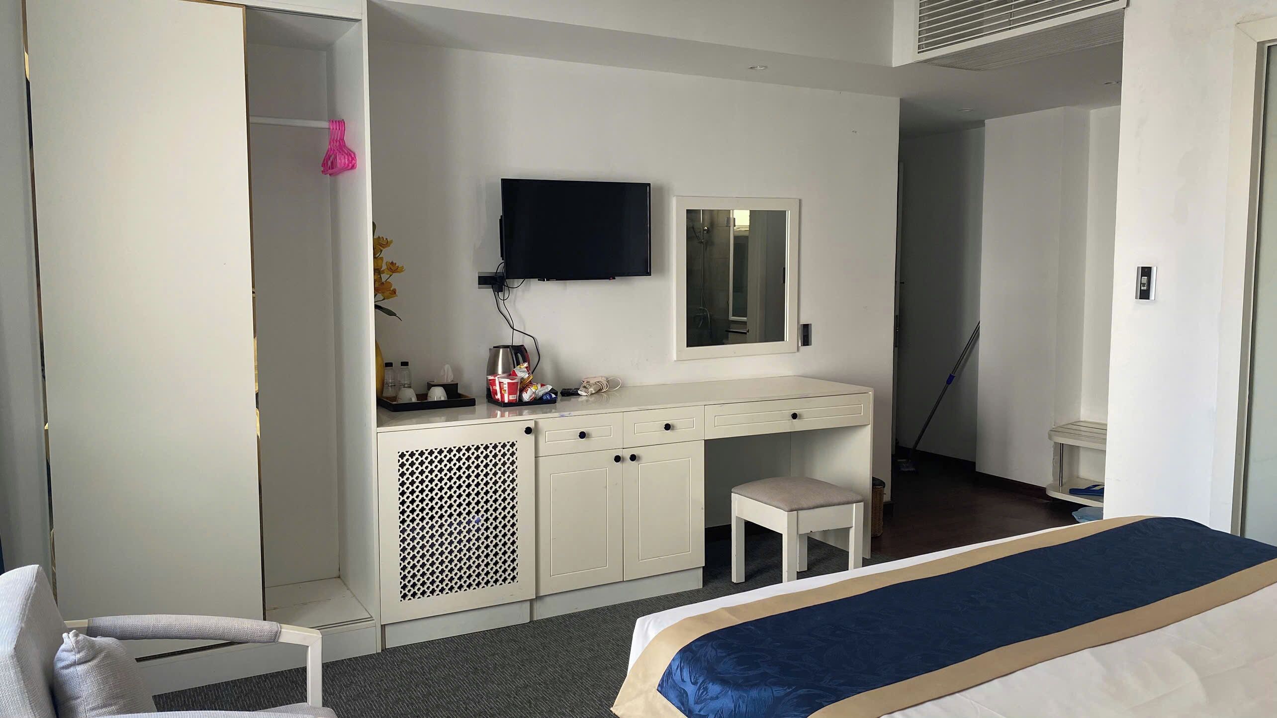 Habitación de hotel con cama, escritorio con espejo, televisión y armario.