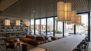 A spacious indoor area with a long table, multiple seating options including sofas and chairs, and large windows offering a view of the city. - Unit 2223 Upside Living (Dubai)