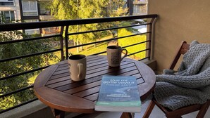 Ein Balkon mit Tisch, Kaffeetasse und Buch.