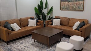 Un salon moderne avec un canapé d’angle, une table basse et deux poufs.