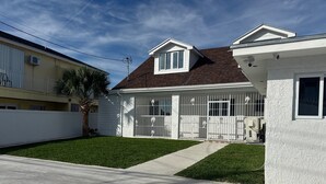 A residential house with a well-maintained lawn, a gated driveway, and a two-story structure with a brown roof and white exterior. - Nassau Hideaway: Steps away from the beach, Down Town, Cable Beach, PI & more.   (Nassau)