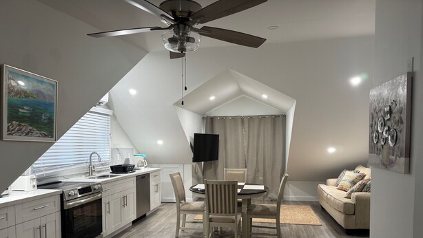 A modern kitchen with a dining area, a ceiling fan, and a TV mounted on the wall. - Nassau Hideaway: Steps away from the beach, Down Town, Cable Beach, PI & more.   (Nassau)