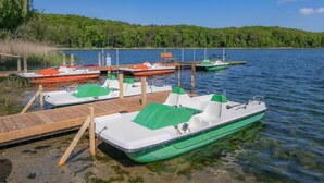 A lake with boats docked at wooden piers, surrounded by a forested area. - Vacation home Angela 1 - Cozy vacation home in the countryside - with fireplace, garden & (Korswandt)