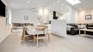 A modern living room with a dining area, a sofa, a coffee table, and a kitchen area.