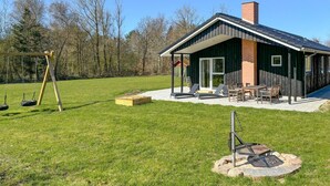 A house with a covered patio, outdoor seating, and a swing set.