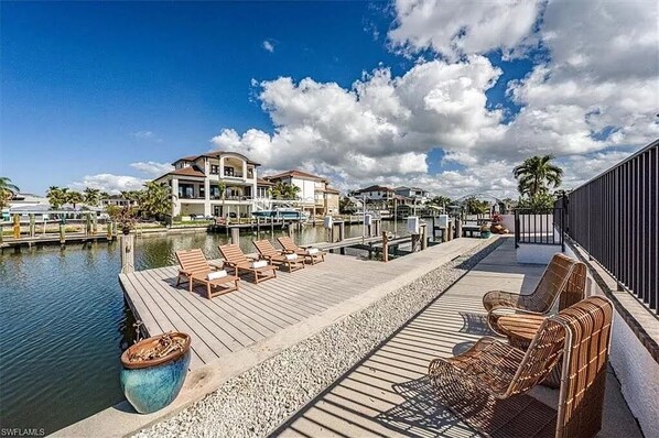 A waterfront property with a dock, lounge chairs, and a large water feature.