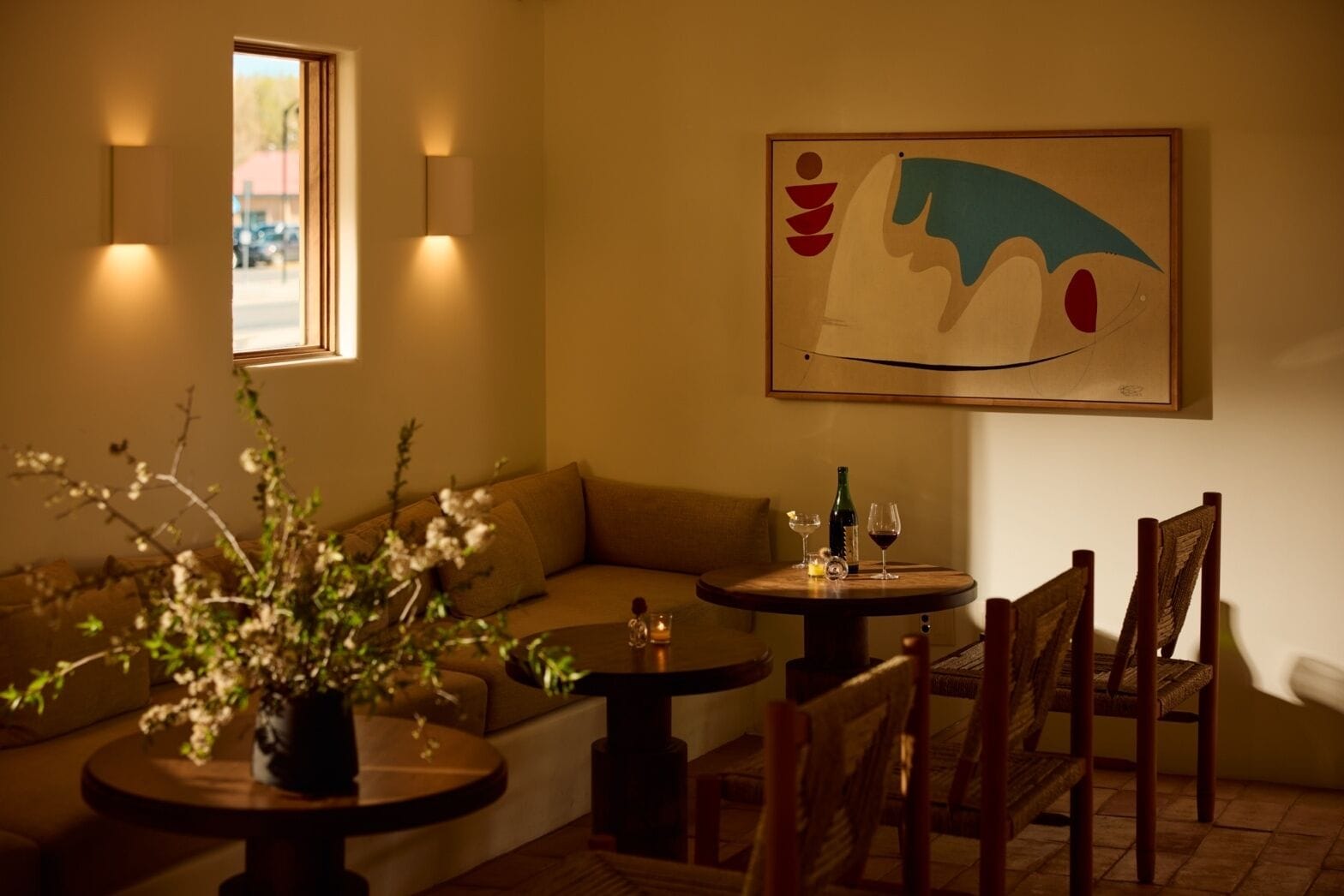 Una habitación acogedora con un sofá, una mesa de comedor con sillas, una mesita con una vela y un cuadro en la pared.