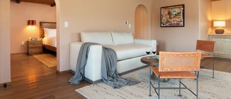 A cozy living room with a white sofa, a wooden ceiling, and a painting on the wall.