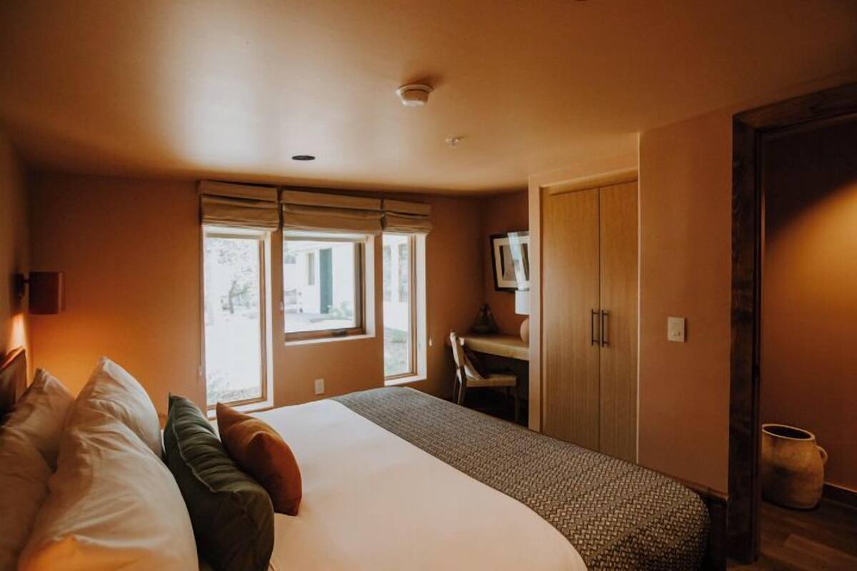 A hotel room with a large bed, a desk, and a wardrobe.