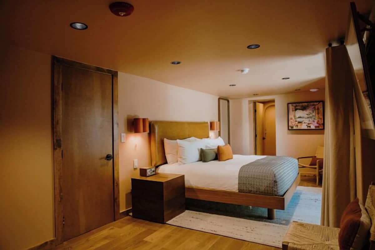 A bedroom with a wooden bed, nightstands, a large window, and a door.