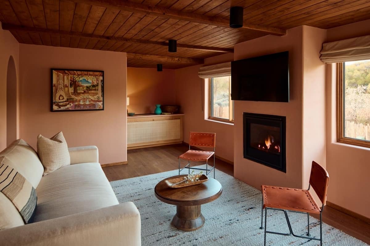 A cozy living room with a fireplace, a sofa, and two chairs.