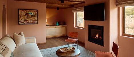 Una sala de estar acogedora con chimenea, un sofá y dos sillones.