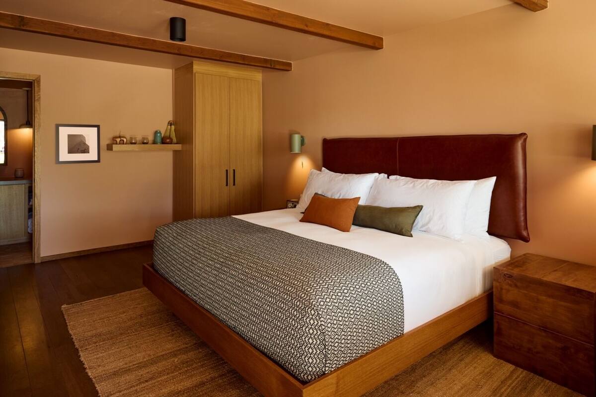 A bedroom with a large bed, wooden headboard, and a nightstand.