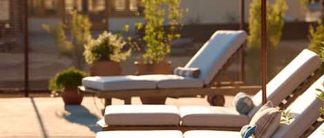 A rooftop lounge area with sun loungers and a large umbrella.