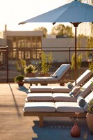 Una piscina al aire libre, sombrillas, tumbonas