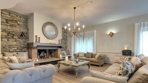 Una sala de estar con pared de piedra, chimenea, dos sofás, una mesa de centro y un candelabro.