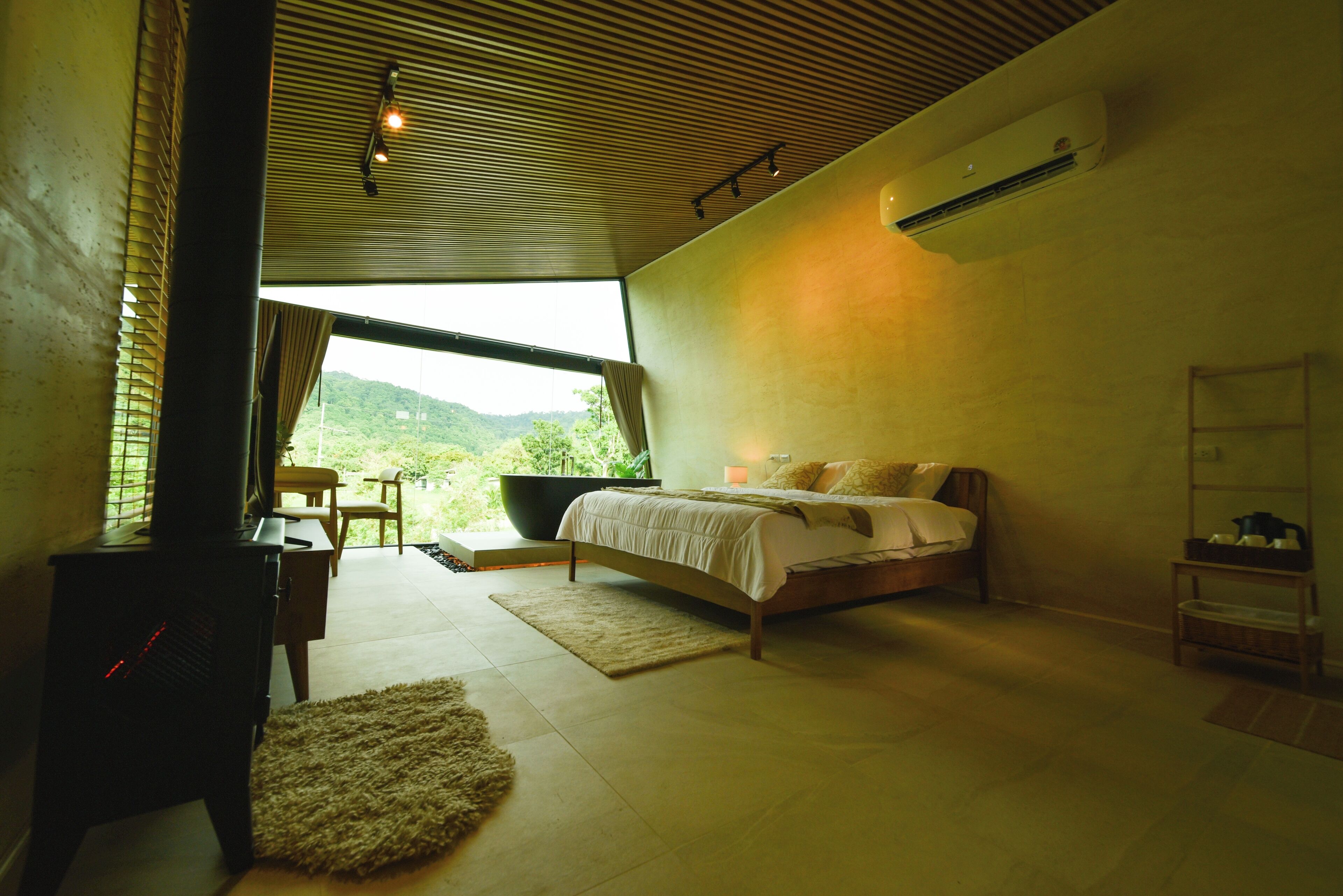 A bedroom with a bed, a desk, and a view of a mountain.