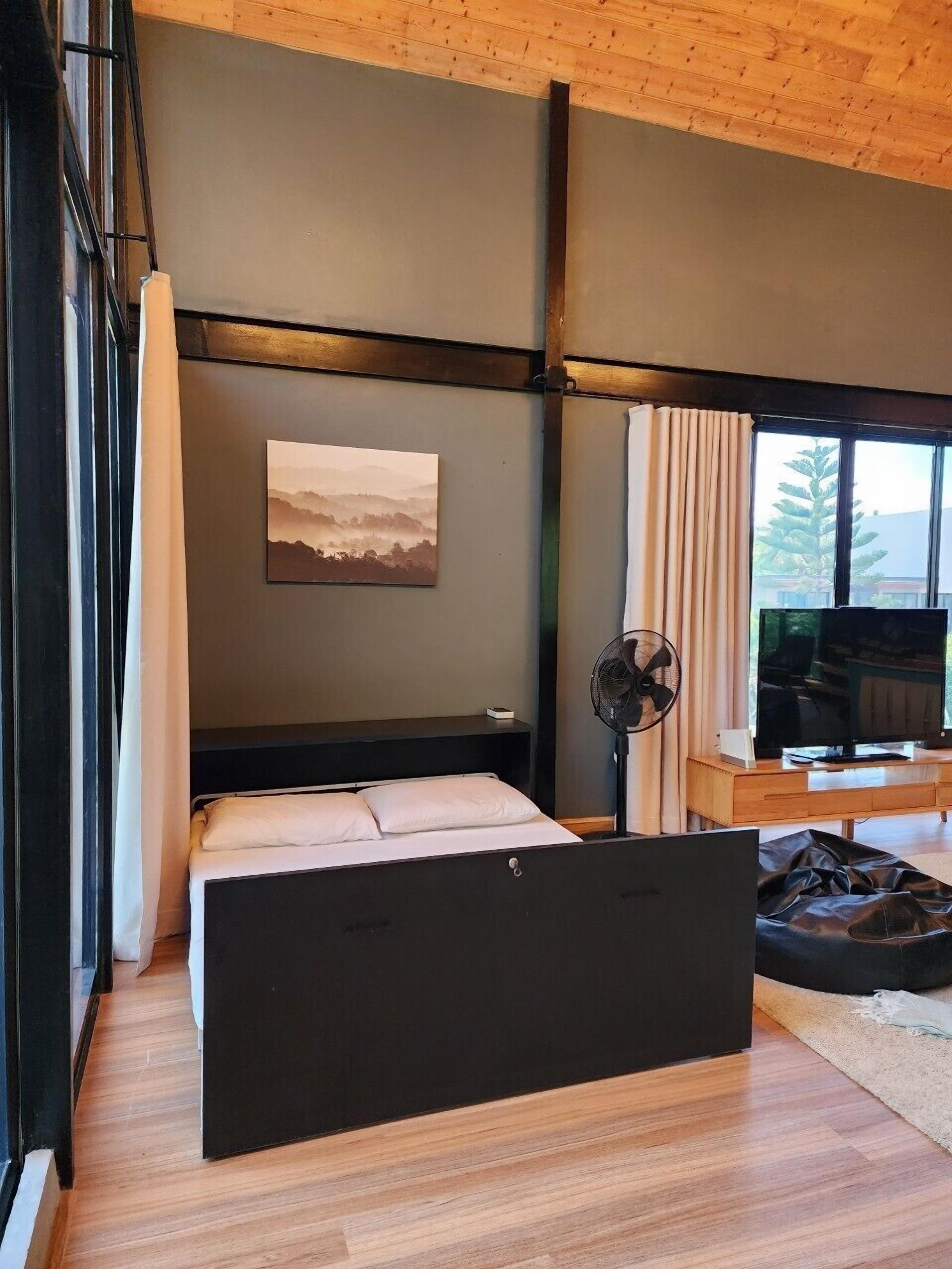 A modern bedroom with a large bed, a TV, and a painting on the wall.