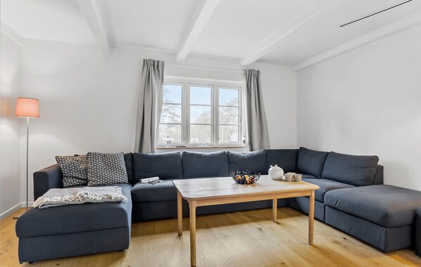 A modern living room with a dark grey sectional sofa, a wooden coffee table, and a floor lamp. - Amazing home in Samsø with WiFi (Samsø)