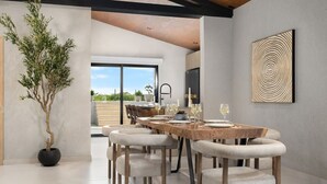 A modern dining area with a wooden table set for six, surrounded by upholstered chairs. A large potted plant is visible to the left.